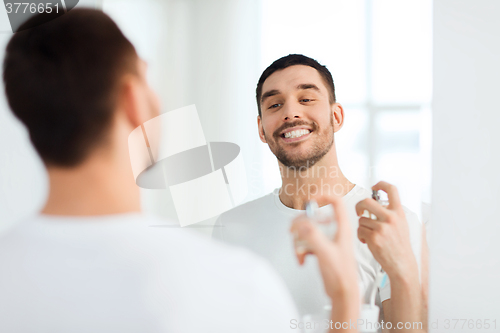 Image of man with perfume looking to mirror at bathroom