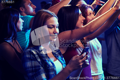 Image of woman with smartphone texting message at concert