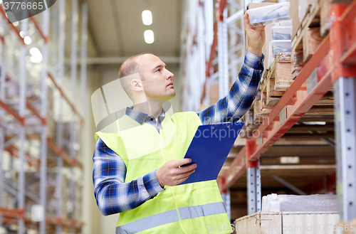 Image of man with clipboard in safety vest at warehouse