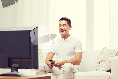 Image of smiling man with remote control watching tv
