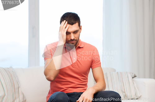 Image of unhappy man suffering from headache at home