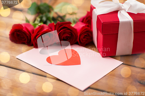 Image of close up of gift box, red roses and greeting card