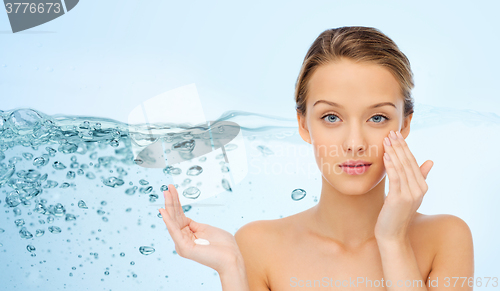 Image of young woman applying cream to her face