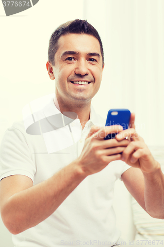 Image of happy man with smartphone at home