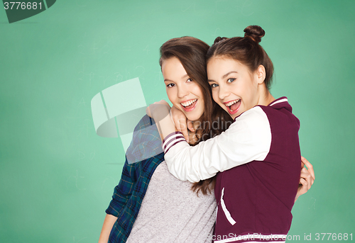 Image of happy teenage girls hugging over green board