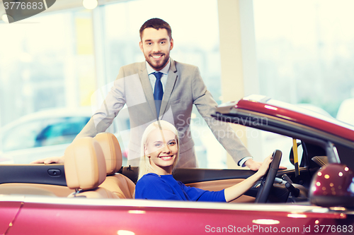 Image of happy couple buying car in auto show or salon