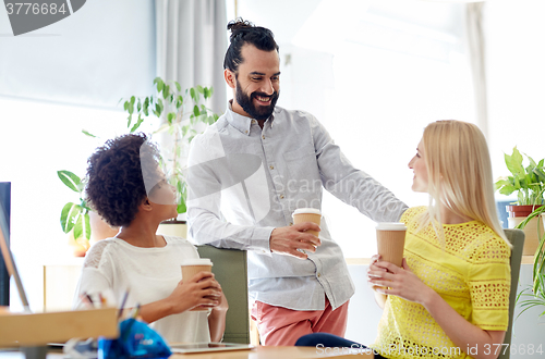 Image of happy creative team drinking coffee in office