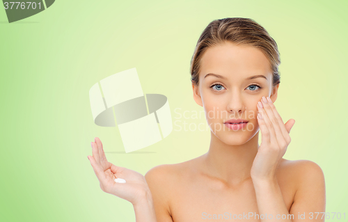 Image of young woman applying cream to her face