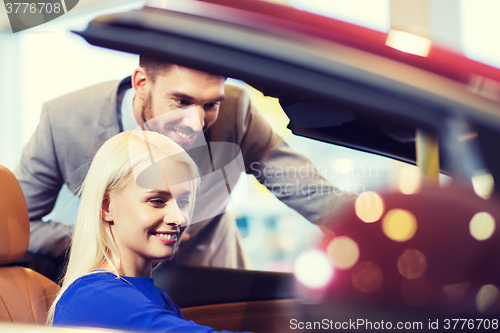 Image of happy couple buying car in auto show or salon