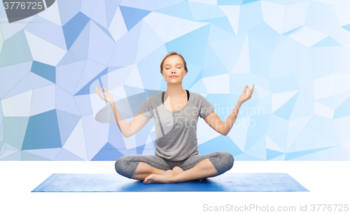 Image of woman making yoga meditation in lotus pose on mat