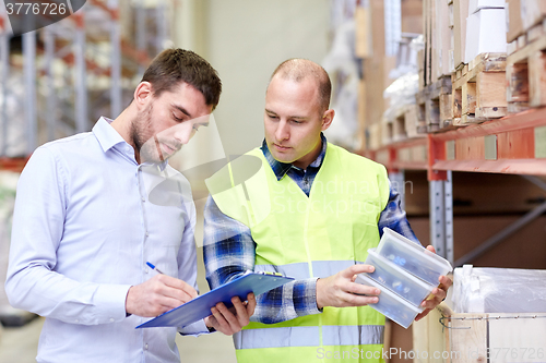 Image of worker and businessmen with clipboard at warehouse