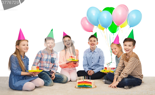 Image of happy children in party hats with birthday cake