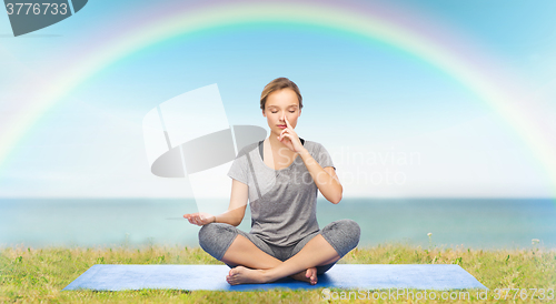 Image of woman making yoga meditation in lotus pose on mat