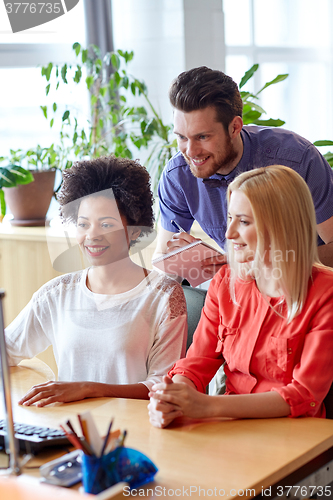 Image of happy creative team with computer in office