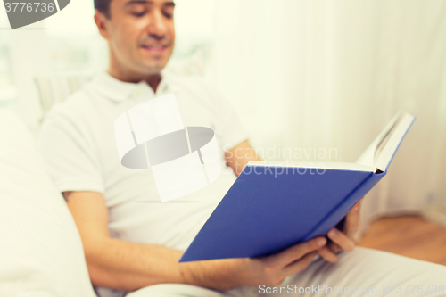Image of close up of happy man reading book at home