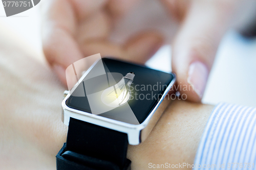 Image of close up of hands with lightbulb on smartwatch