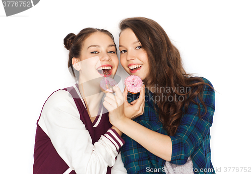 Image of happy pretty teenage girls eating donuts