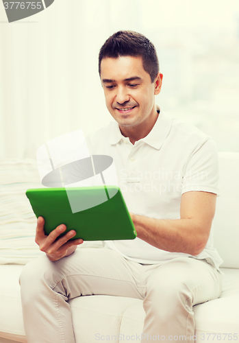 Image of smiling man working with tablet pc at home