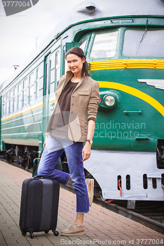 Image of beautiful middle-aged woman with luggage on a railway platform n