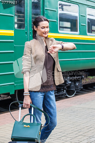 Image of beautiful woman looks at his watch on the platform of the railwa