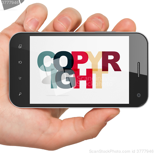 Image of Law concept: Hand Holding Smartphone with Copyright on  display