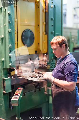 Image of Senior woman stamps details on hydraulic press