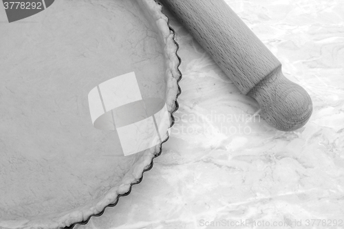 Image of Baking tin lined with pastry, wooden rolling pin beside