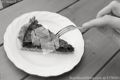 Image of Woman uses dessert fork to cut into a slice of pecan pie