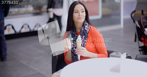 Image of Woman eating an ice cream in a parlor or cafe