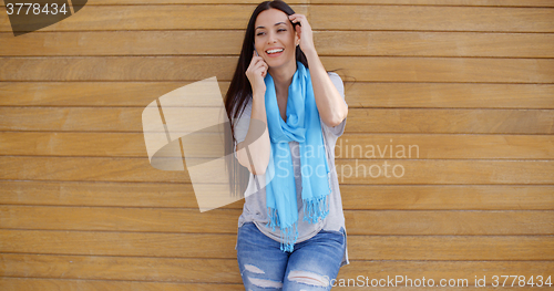 Image of Woman on phone and leaning against wall