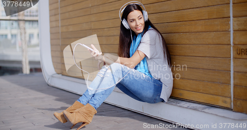 Image of Pretty trendy young woman enjoying her music