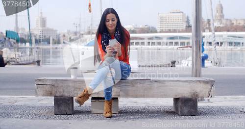 Image of Young woman sitting on a bench in town