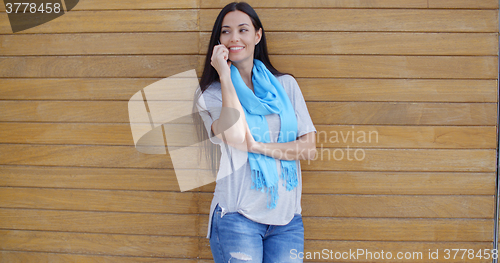 Image of Woman on phone and leaning against wall