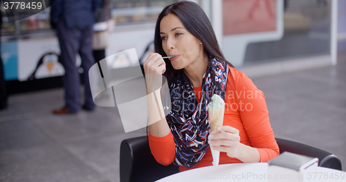 Image of Woman eating an ice cream in a parlor or cafe