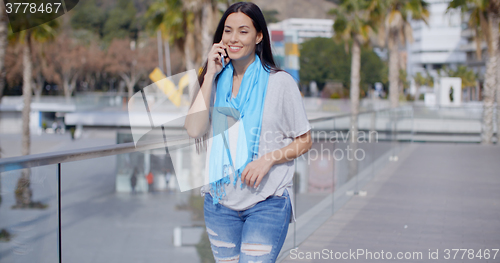 Image of Woman walking along a promenade with mobile