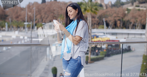 Image of Grinning woman using phone on overpass