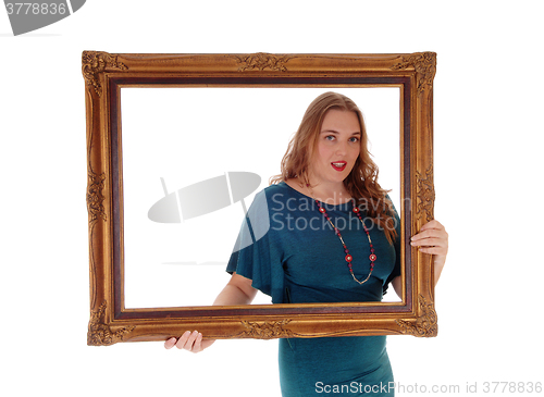 Image of Woman holding and looking trough picture frame.