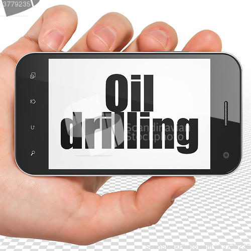 Image of Industry concept: Hand Holding Smartphone with Oil Drilling on display