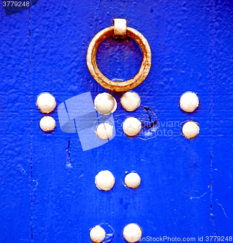 Image of rusty metal     nail dirty stripped paint in the blue wood door 