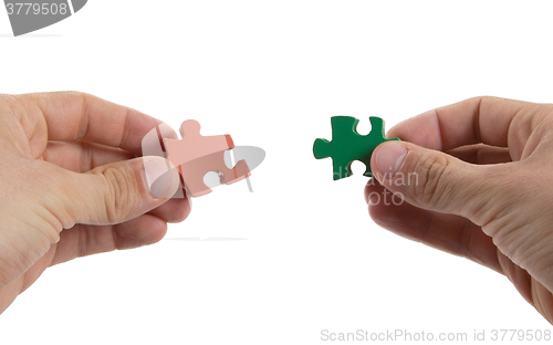 Image of Close-up of hands trying to connect big jigsaw puzzle pieces