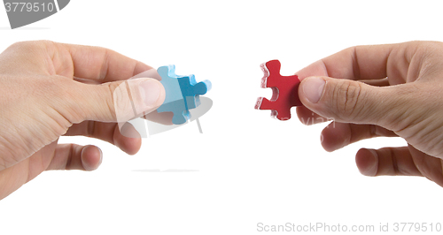 Image of Close-up of hands trying to connect big jigsaw puzzle pieces