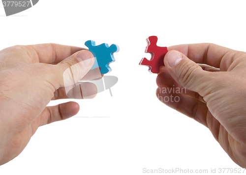 Image of Close-up of hands trying to connect big jigsaw puzzle pieces