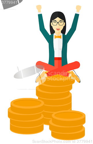 Image of Happy business woman sitting on coins.