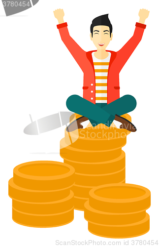 Image of  Happy businessman sitting on coins.