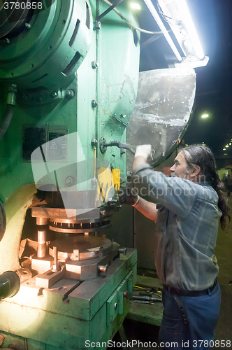 Image of Elderly worker adjusts machine