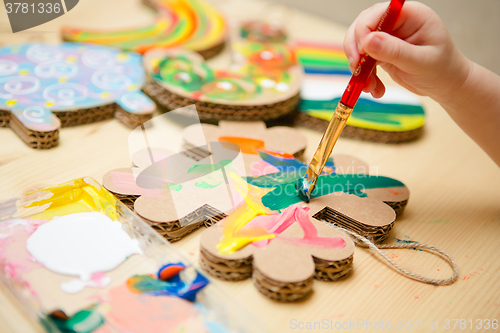 Image of Little female baby painting with colorful paints