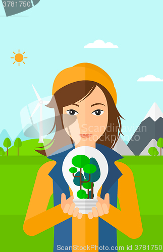 Image of Woman with lightbulb and trees inside.