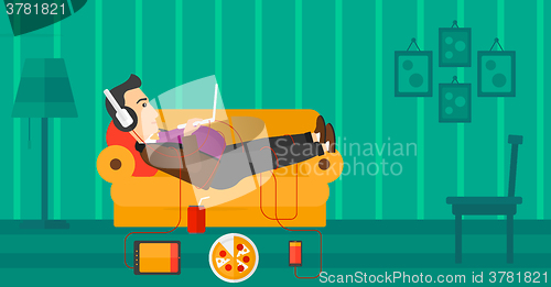 Image of Man lying on sofa with many gadgets.
