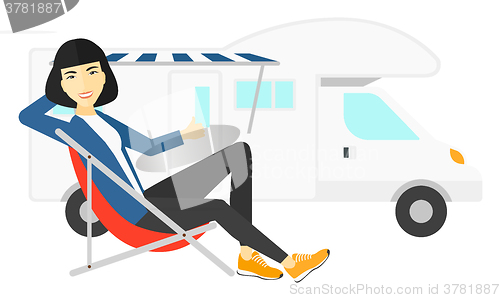 Image of Woman sitting in front of motorhome.