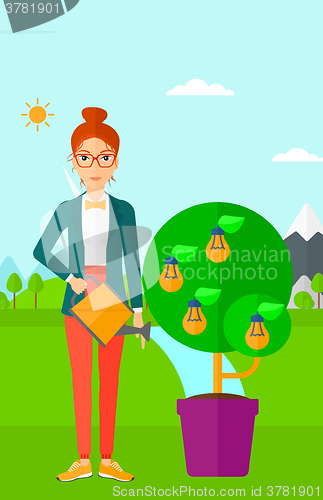 Image of Woman watering tree with light bulbs.